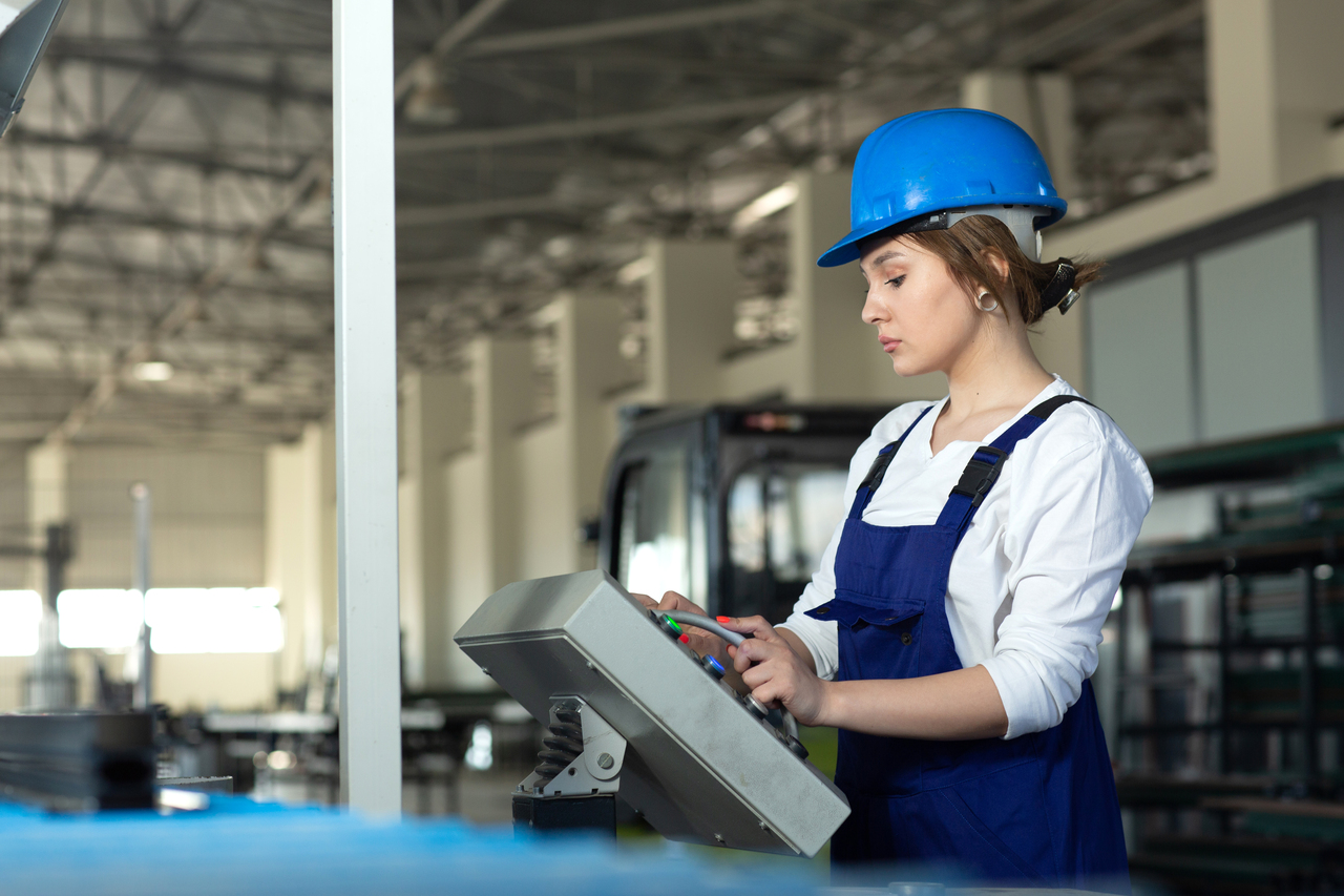 front-view-young-attractive-lady-blue-construction-suit-helmet-controlling-machines-hangar-working-daytime-buildings-architecture-construction-4